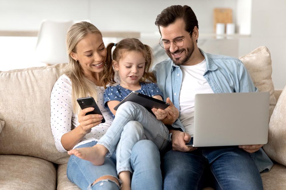 Happy bonding family couple and little kid using different gadge